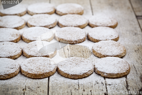 Image of Fresh baked oat cookies with sugar powder on rustic wooden table