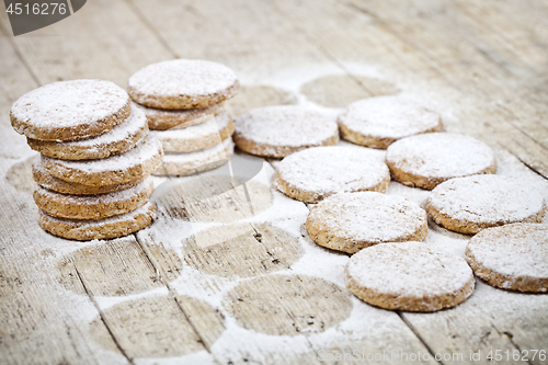 Image of Fresh baked oat cookies with sugar powder on rustic wooden table