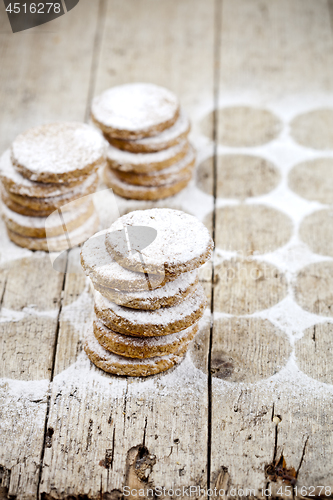 Image of Fresh baked oat cookies with sugar powder on rustic wooden table