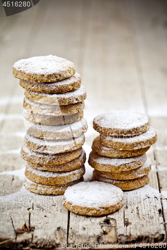 Image of Fresh oat cookies stacks with sugar powder closeup on rustic woo