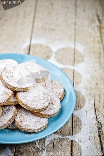 Image of Fresh baked oat cookies with sugar powderon blue ceramic plate o