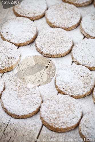 Image of Fresh baked oat cookies with sugar powder on rustic wooden table