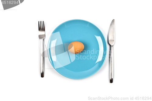 Image of Fresh chicken boiled egg on blue plate, fork and knife on white 