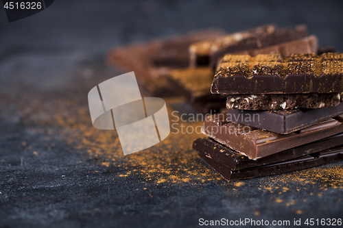 Image of Broken chocolate stacked on black background. Chocolate bar piec