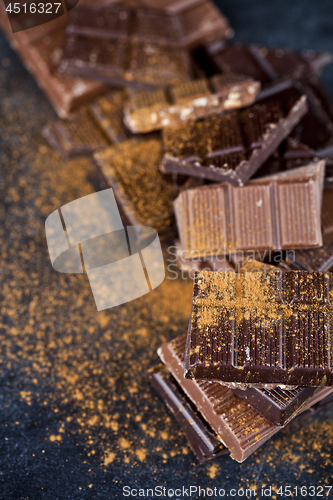 Image of Broken chocolate stacked on black background. Chocolate bar piec