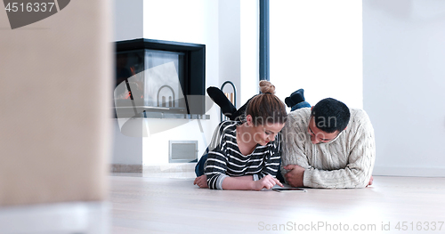 Image of Young Couple using digital tablet on the floor