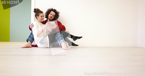 Image of Young Couple using digital tablet on the floor