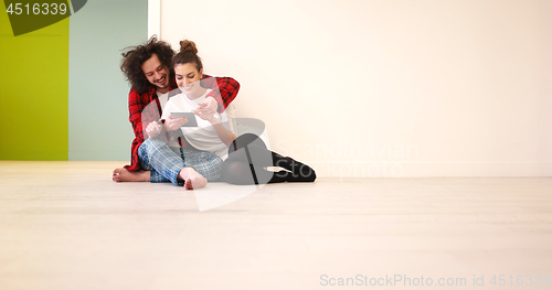 Image of Young Couple using digital tablet on the floor