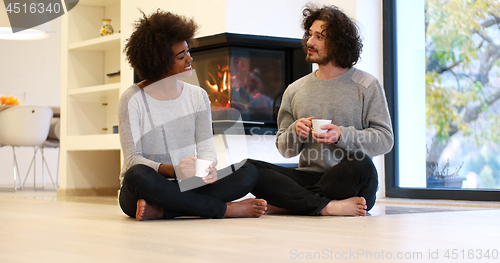 Image of multiethnic couple  in front of fireplace