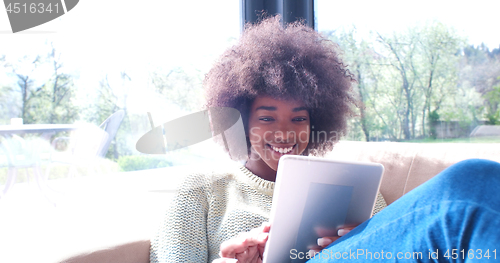 Image of african american woman at home using digital tablet