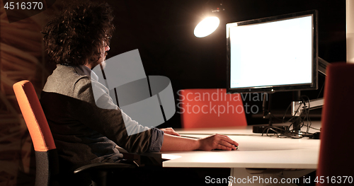 Image of man working on computer in dark office