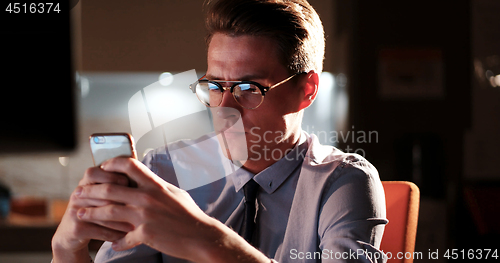 Image of man using mobile phone in dark office