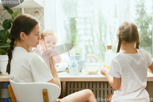 Image of The happy smiling caucasian family in the kitchen preparing breakfast