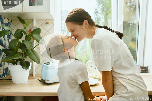 Image of The happy smiling caucasian family in the kitchen preparing breakfast