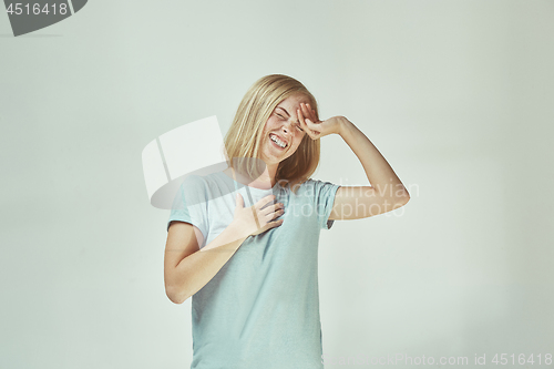 Image of The happy freckled woman standing and smiling against gray background.