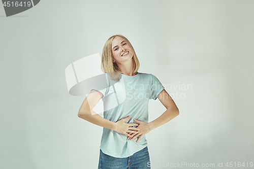 Image of The happy freckled woman standing and smiling against gray background.