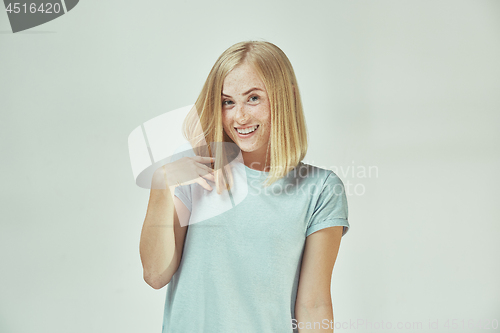 Image of The happy freckled woman standing and smiling against gray background.