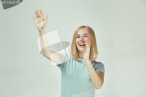 Image of The happy freckled woman standing and smiling against gray background.