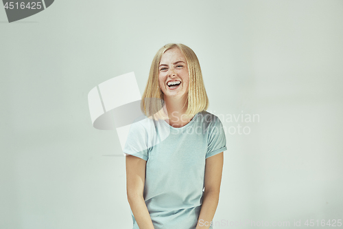 Image of The happy freckled woman standing and smiling against gray background.