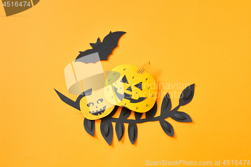 Image of Flying bat, leaves and scary pumpkins on an orange background with copy space. Paper handcraft composition to Halloween. Flat lay