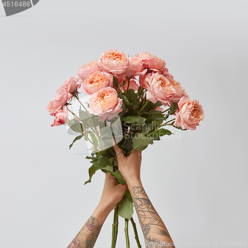 Image of the girl is holding a bouquet of fresh pink roses,