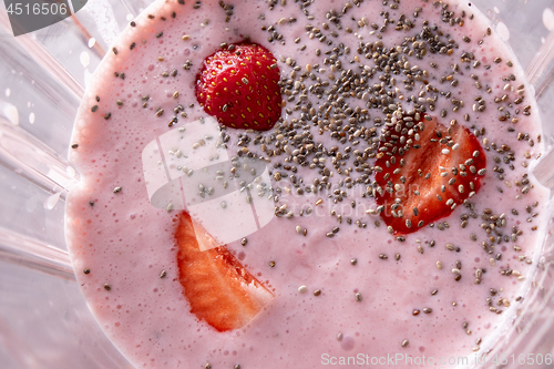 Image of The process of preparing pink healthy cocktail with strawberries in a kitchen blender, close up. Top view