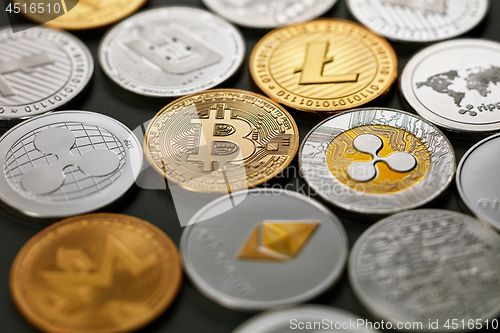 Image of Set of different gold and silver coins of crypto-currencies on a dark background with bright light. Top view