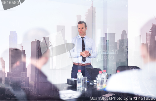 Image of Confident company leader on business meeting against new york city manhattan buildings and skyscrapers window reflection.