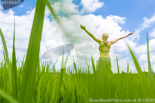 Image of Relaxed healthy sporty woman, arms rised to the sky, enjoying pure nature at beautiful green rice fields on Bali.