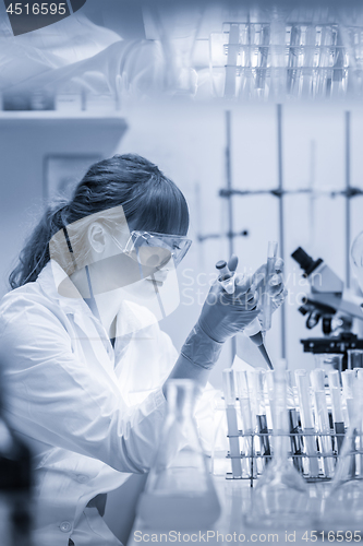 Image of Young scientist pipetting in life science laboratory.