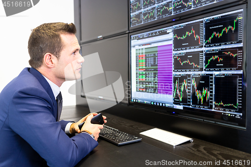 Image of Stock broker trading online, talking on mobile phone.