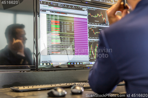 Image of Stock broker trading online, talking on mobile phone.