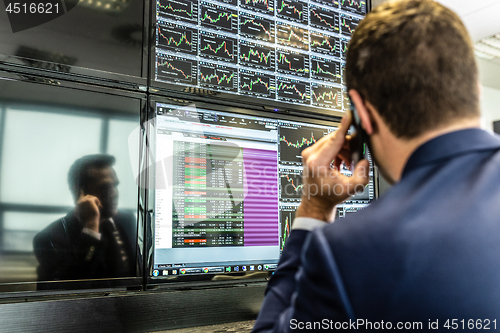 Image of Stock broker trading online, talking on mobile phone.