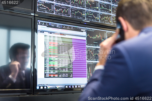 Image of Stock broker trading online, talking on mobile phone.