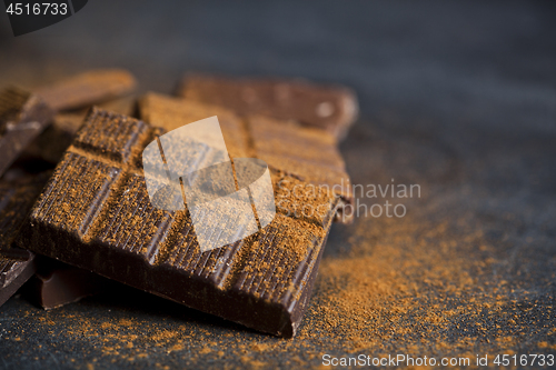 Image of Chocolate stacked on black background. Chocolate bar pieces heap