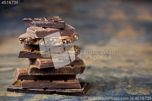 Image of Broken chocolate stacked on black background. Chocolate bar piec