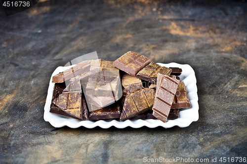 Image of Chocolate bar pieces heap witn cinnamon powder on white ceramic 