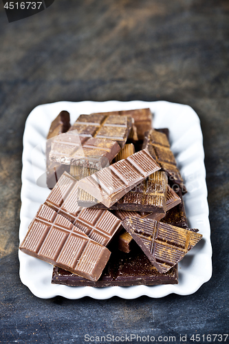 Image of Chocolate bar pieces heap witn cinnamon powder on white ceramic 