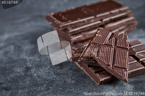 Image of  Chunks of broken chocolate stacked on grey background.