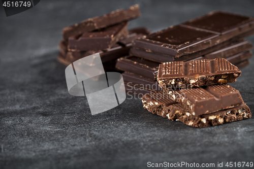 Image of Chunks of broken chocolate stacked on black board. 