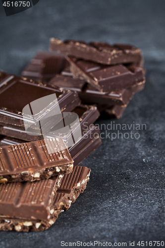 Image of Chunks of broken chocolate stacked on black board. 