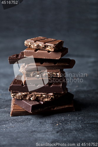 Image of Chunks of broken chocolate stacked on black board.