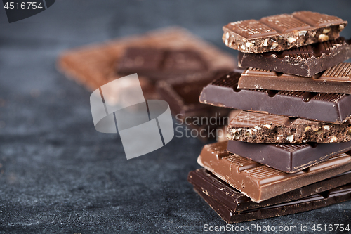 Image of Chunks of broken chocolate stacked on black board.