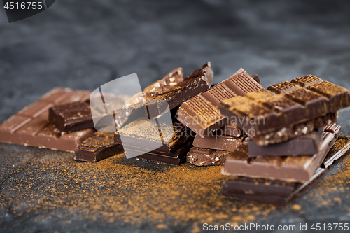 Image of Broken chocolate stacked on black background. Chocolate bar piec