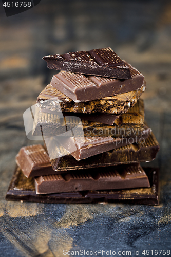 Image of Broken chocolate stacked on black background. Chocolate bar piec