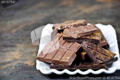 Image of Chocolate bars pieces heap witn cinnamon powder on white ceramic