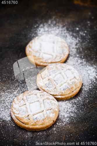 Image of Fresh baked tarts with chocolate filling and sugar powder on bla