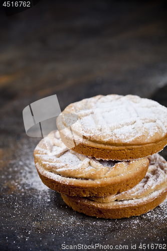 Image of Fresh baked tarts with chocolate filling and sugar powder on bla