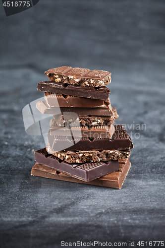 Image of Chocolate bar pieces stack on black background. Sweet food photo