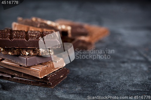 Image of Chunks of broken chocolate stacked on black board. Chocolate bar